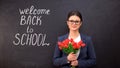 Lady teacher smiling and holding bunch of tulips, welcome back to school written