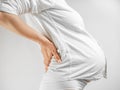 Lady in the third trimester of pregnancy. A pregnant woman in white shirt grabbed her lower back white background. The