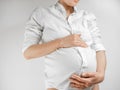 Lady in the third trimester of pregnancy. A pregnant young woman in white shirt grabbed her belly white background. A