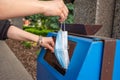 Lady throwing away a used mask in blue dump. Example of improper disposal of medical masks. Coronavirus masks disposal concept Royalty Free Stock Photo