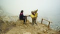 A lady tourist with a traditional sulfur miner in Ijen crater, Banyuwangi, Indonesia