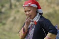 Lady in traditional Red Dzao hill tribe dress eats fruit in Sapa, Vietnam.