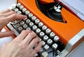 Lady typing orange vintage typewriter