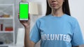 Lady volunteer demonstrating prekeyed smartphone to camera, charity application