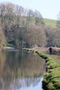 Lady walking along canal towpath in countryside Royalty Free Stock Photo