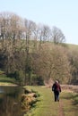 Lady walking along canal towpath in countryside