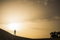 Lady walking on a dune desert in maspalomas canary islands during a golden smazing beautiful sunset with orange and yellow colors Royalty Free Stock Photo