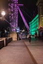 A lady walking by the London Eye at night