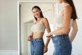 Lady Wearing Jeans After Slimming Comparing Size Near Mirror Indoors Royalty Free Stock Photo