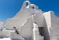 Lady in white dress sits at the stairs of the Paraportiani Church of Mykonos, Greece Royalty Free Stock Photo