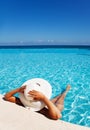 Lady with white hat relaxes in swimming pool