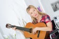 Lady woman musican on wheelchair playing guitar at home