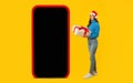 lady with Xmas gift showcases huge phone mockup, yellow background