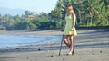 Lady in a yellow sundress with crutches looking into the distance on sandy beach Royalty Free Stock Photo