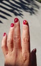 Ladybug on fingers with red nails, red atmosphere.