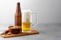 Lager beer pouring in glass and bottle with salted peanuts Royalty Free Stock Photo