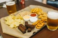 Lager beer and snacks on wooden table. Nuts, chips, peanut, toast, crackers. Appetizer fast food. Craft beer. Beerboard Royalty Free Stock Photo