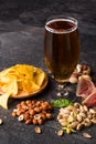 Lager full of dark beer. Chips, salty nuts and meat with a cold alcoholic beer on a black table background. Copy space. Royalty Free Stock Photo