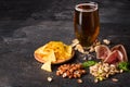 Lager full of fresh beer. Different nuts, chips, and meat with an alcoholic beer on a black background. Copy space. Royalty Free Stock Photo