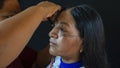 Woman of the Quichua ethnic group of the Ecuadorian Amazon applying makeup to her sister`s face in traditional dress on a black