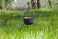 Lagre touristic cauldron on a tripod among forest glade with green grass