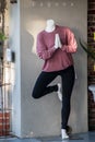 Headless praying mannequin wearing a pink shirt and black leggings