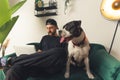 Laid-back caucasian bearded man petting his dog while working on a laptop in his modern apartment. Best man& x27;s friend Royalty Free Stock Photo