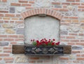 Laid down antique semicircular window in a brick wall with a flowerpot, close-up