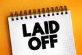 Laid Off - means that your employer is terminating your contract, text concept on notepad
