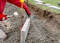 Laing edging kerb on semidry concrete during roadworks and new footpath construction by groundworker wearing safety gloves Royalty Free Stock Photo