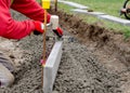 Laing edging kerb on semidry concrete during roadworks and new footpath construction by the groundworker wearing safety gloves Royalty Free Stock Photo