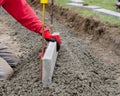 Laing edging kerb on semidry concrete during roadworks and new footpath construction by groundworker wearing safety gloves Royalty Free Stock Photo