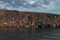 Lake Baikal, Rocky red stones shore with cliffs, reflection in ripples