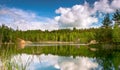 Lake with banks in bright spring green mixed forest with reflection of blue sky with clouds in clear water. Royalty Free Stock Photo