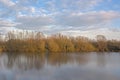 Lake with bare trees under a cloudy sky in the flemish countryside