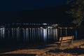 Lake beach bench by sidewalk at night illuminated with street lantern. Zell am see Austria Royalty Free Stock Photo