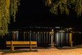 Lake beach bench by sidewalk at night illuminated with street lantern. Zell am see Austria Royalty Free Stock Photo