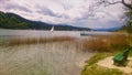 a lake with a bench and a sailing boat in the middle