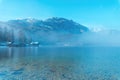 Lake Bohinj landscape in winter morning, fog rising over clean glacial water in slovenian national park Triglav Royalty Free Stock Photo