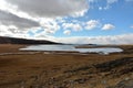 A lake bound by the first ice, surrounded by mountain ranges in the autumn steppe under a cloudy sky Royalty Free Stock Photo