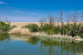 A lake with a calm water, blue sky and reflected vegetation.