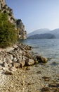 Lake clear water and shingle beach under steep rocks, near Riva
