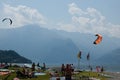 Lake Como, Italy - July 21, 2019: People resting on beach near lake. Windsurfers and kitesurfers preparing equipment for surfing.