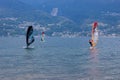 Lake Como, Italy - July 21, 2019. Water sport: group of three windsurfers riding on a sunny summer day near the Colico, town in