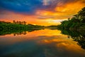 Lake in an dramatic sunset. Lake surrounded by trees at sunset with orange sky and clouds in bluish gray tones forming a beautiful Royalty Free Stock Photo