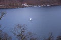 lake at the foot of a mountain surrounded by low mountains in autumn or winter surrounded by trees without leaves under Royalty Free Stock Photo