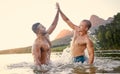 Lake, high five and swimming with man friends outdoor in nature for travel or adventure while on summer holiday Royalty Free Stock Photo