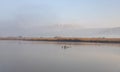 Lake  Hula against the background of the snow-capped peak of Mount Hermon on a foggy early winter morning in the nature reserve at Royalty Free Stock Photo