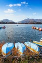 Lake Kawaguchiko row boat stranded on shore with water bike boat pier in background. Japan