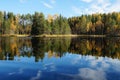 Lake Kodari in autumn, the lake shore is reflected in the calm smooth water. Green pines, yellow deciduous trees. Royalty Free Stock Photo